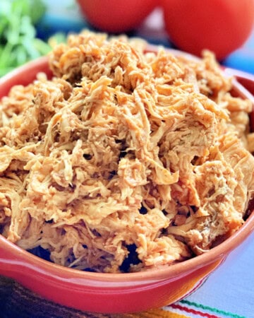 Red bowl filled with shredded chicken.