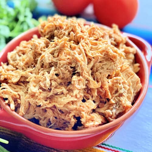 Red bowl filled with shredded chicken.