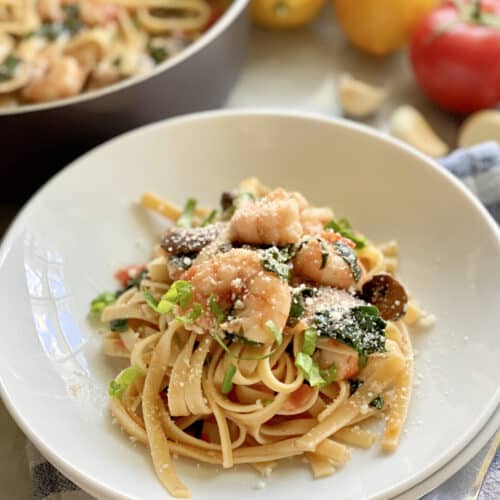 Linguini topped with shrimp nestled in a white bowl.
