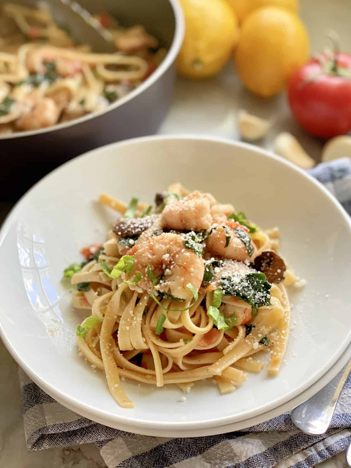 Linguini topped with shrimp nestled in a white bowl.