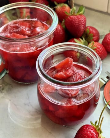 Close up of two glass jars filled with strawberry sauce.