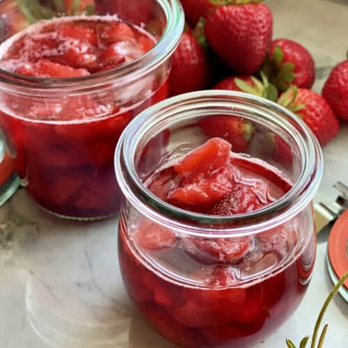 Close up of two glass jars filled with strawberry sauce.