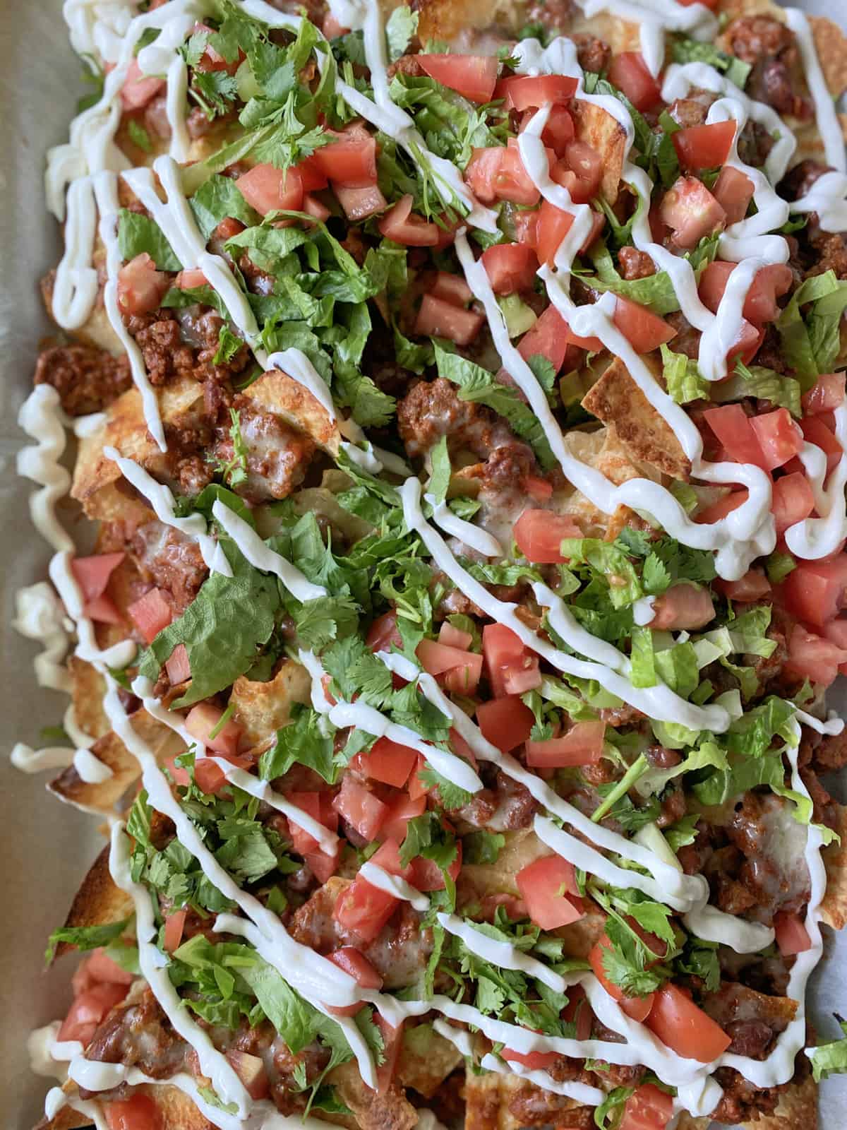 Close up of chili cheese nachos on a baking sheet.