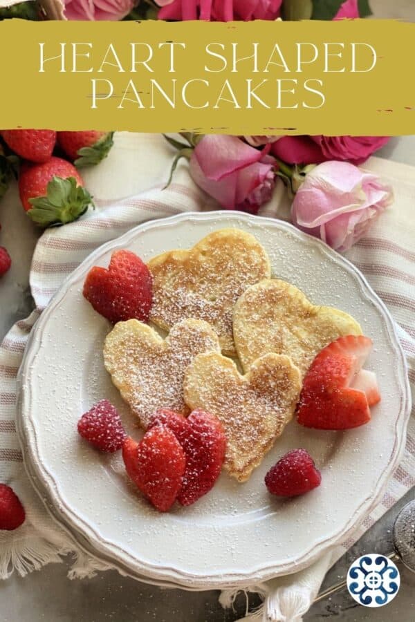 White plate with heart shaped pancakes sprinkled with powder sugar with text on image for Pinterest.