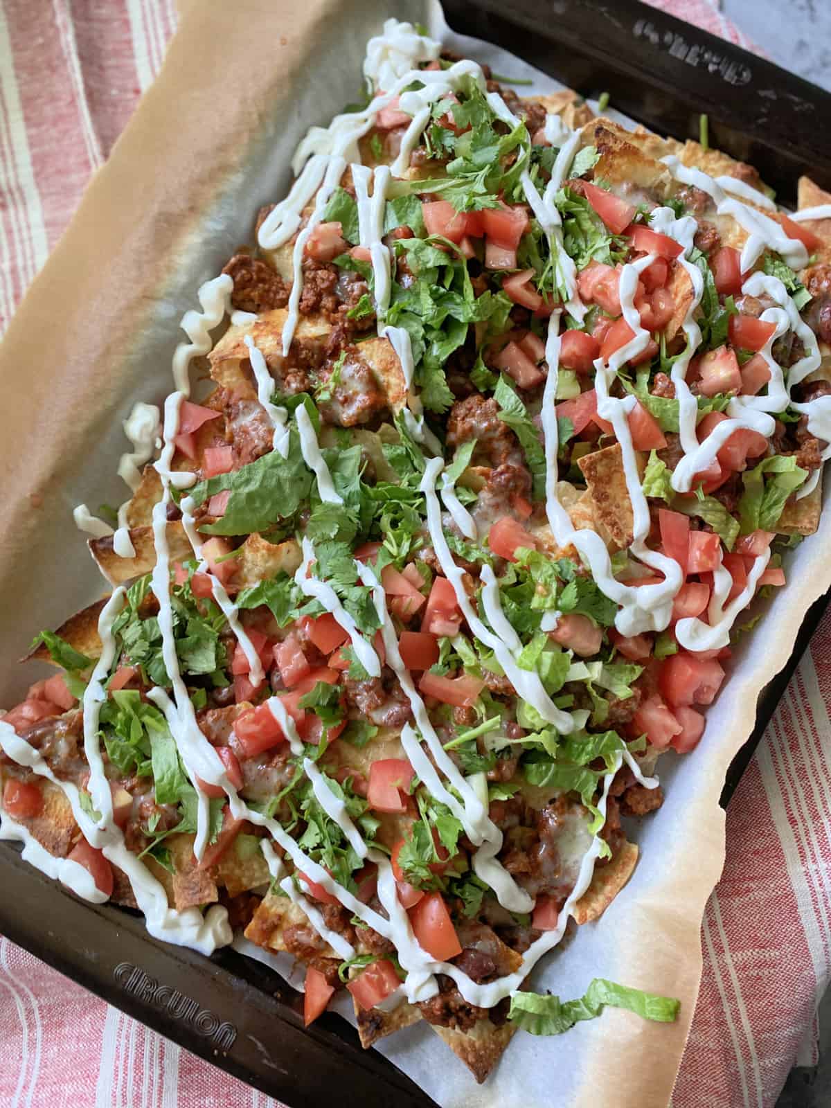 Top view of a brown sheet pan filled with loaded chili cheese nachos.