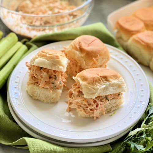 White plate filled with three small sandwiches stuffed with chicken salad.