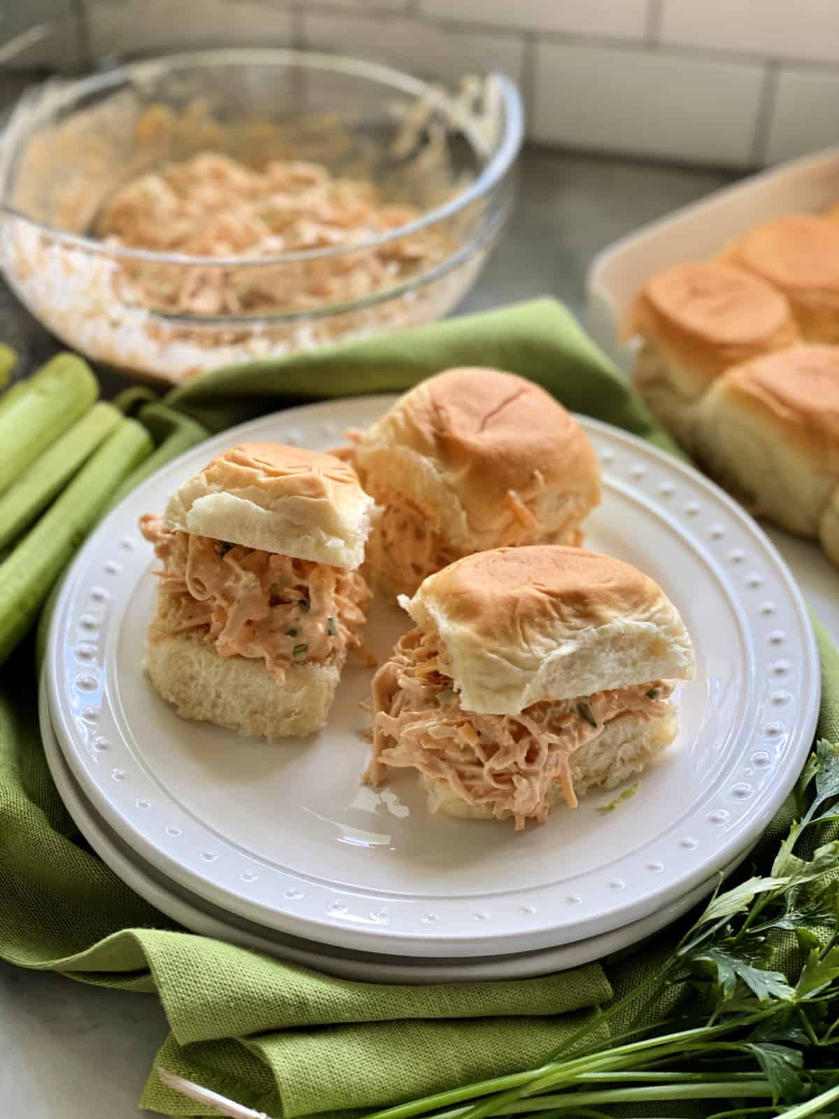 Three buffalo chicken sandwiches on white plate.