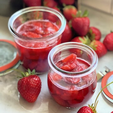 Two glass jars filled with strawberry sauce.
