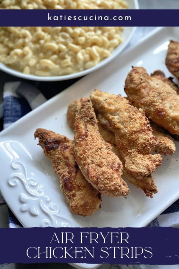 8 chicken strips on a white platter with mac and cheese bowl next to it.