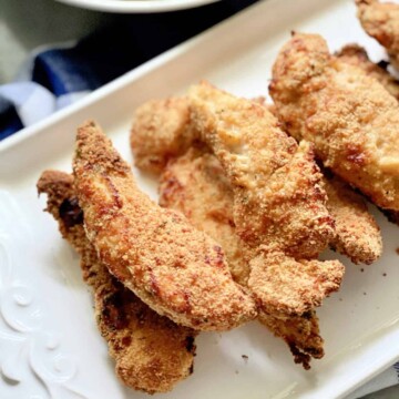 6 chicken strips on a white platter.