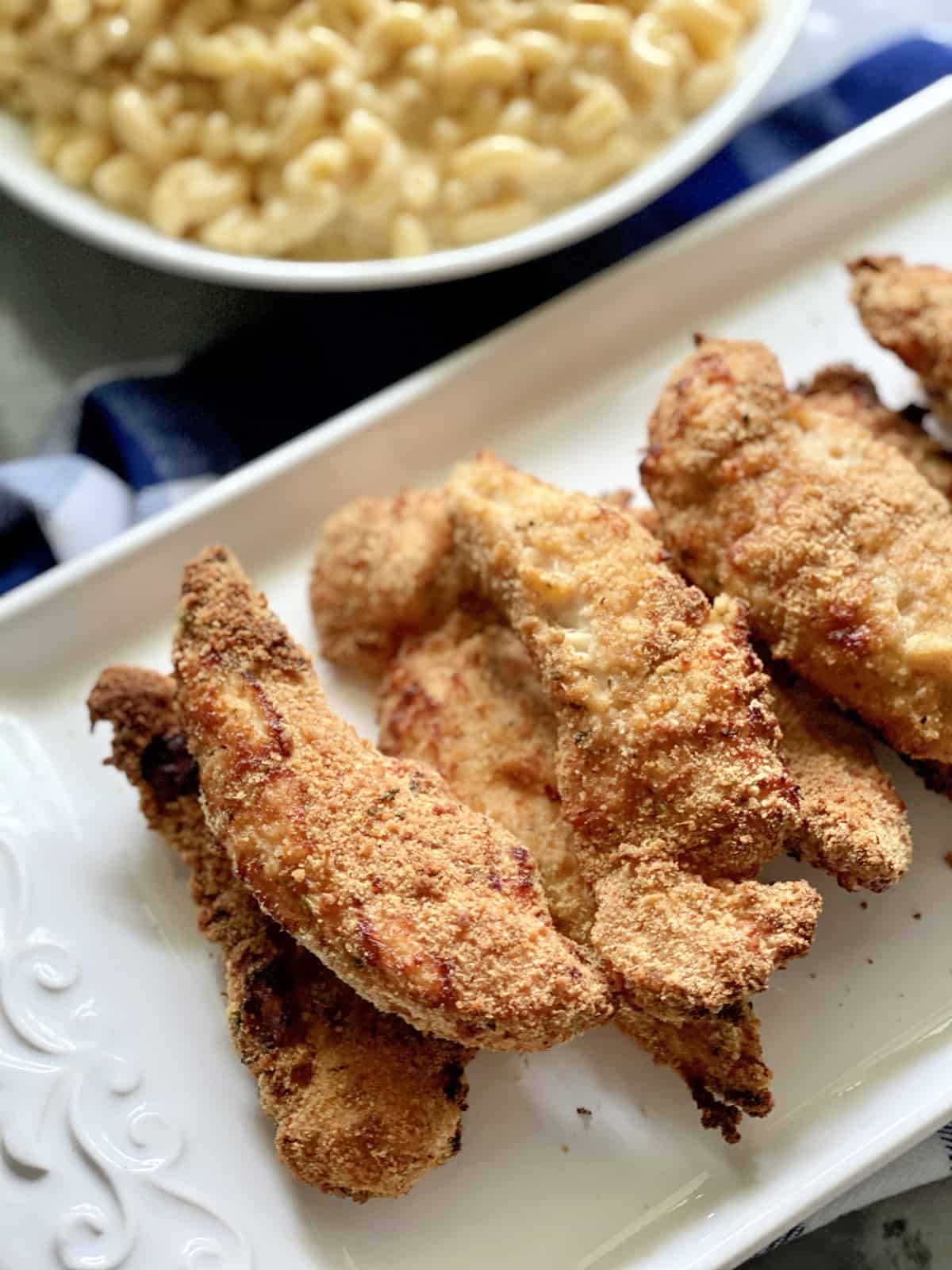 Golden breaded chicken tenders stacked on a white platter.