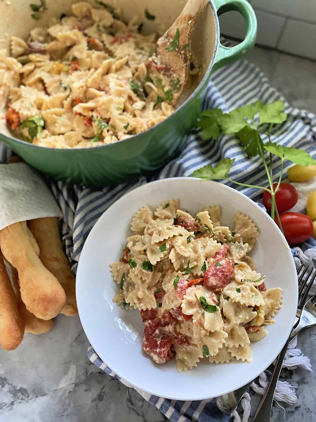 Top view of a bowl and a pot filled with bow tie pasta and cheese and tomato sauce.