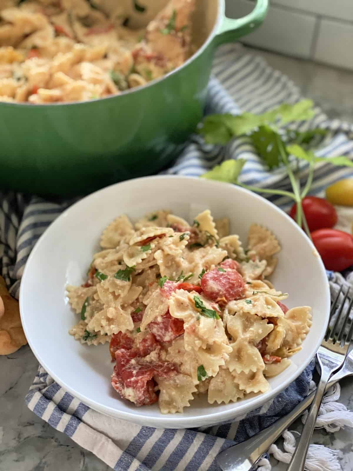 White bowl filled with bow tie pasta in cheese sauce.