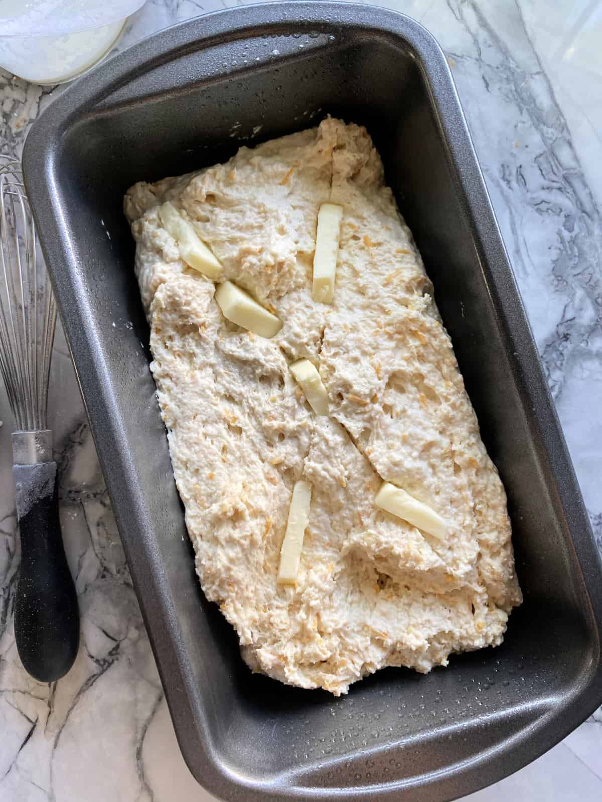 Top view of raw dough cut in with butter in a loaf pan.