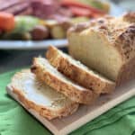 Three slices of bread cut from a loaf with dinner in the background.