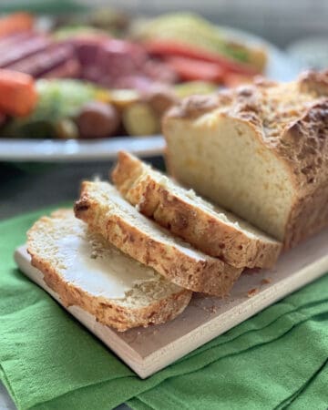 Three slices of bread cut from a loaf with dinner in the background.