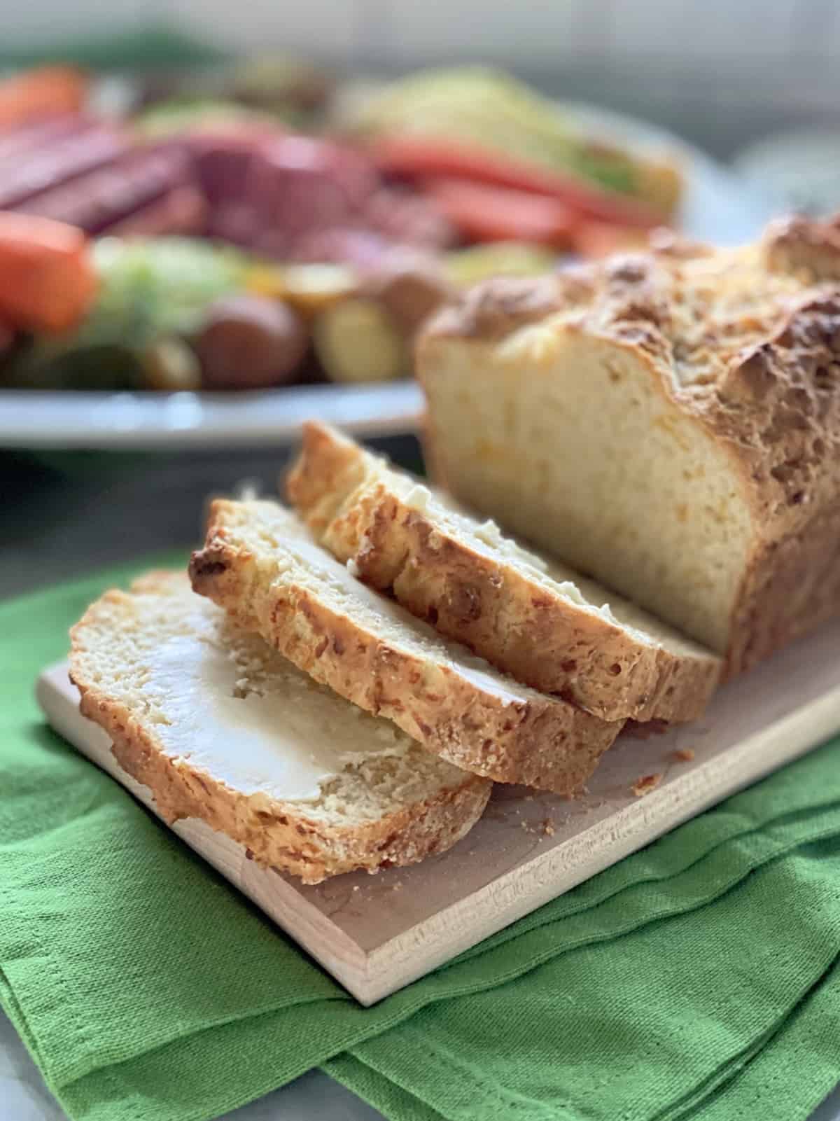 Three slices of bread cut from a loaf with dinner in the background.