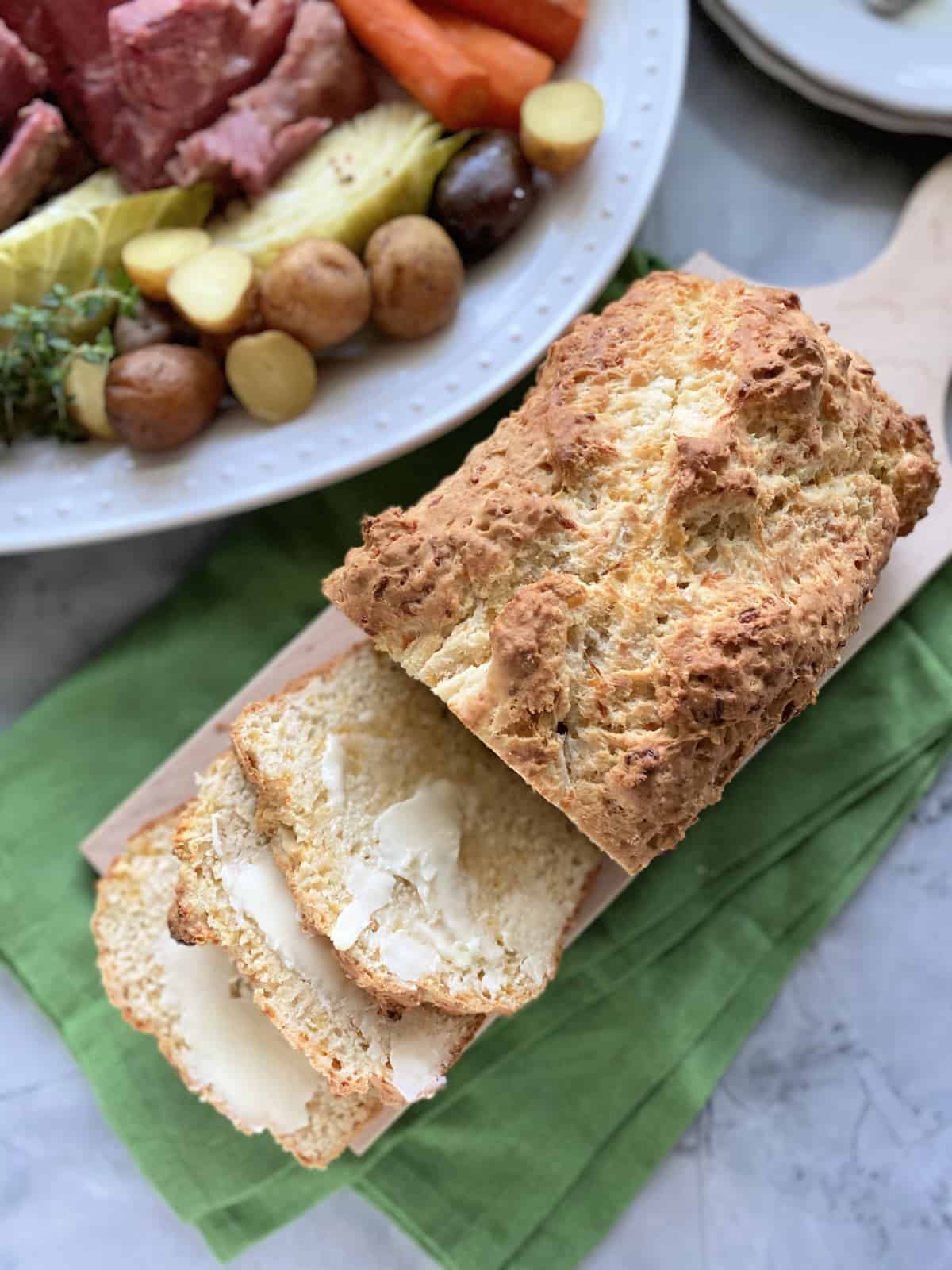 Top view of a loaf of bread with three buttered slices.