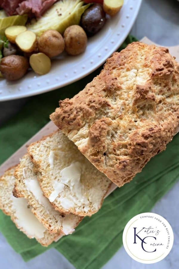 Top view of a loaf of bread with three slices cut with butter and logo on right corner of photo.