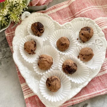 Top view of heart shaped plate filled with 8 truffles sitting on a red and white stripped cloth.