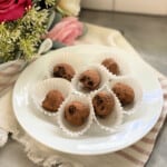 White plate filled with 6 chocolate truffles in white liners.