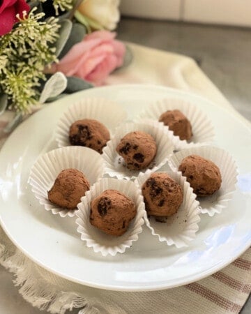 White plate filled with 6 chocolate truffles in white liners.