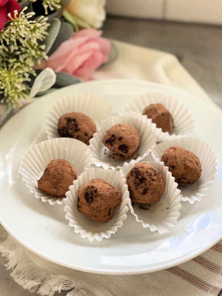 White plate filled with 6 chocolate truffles in white liners.