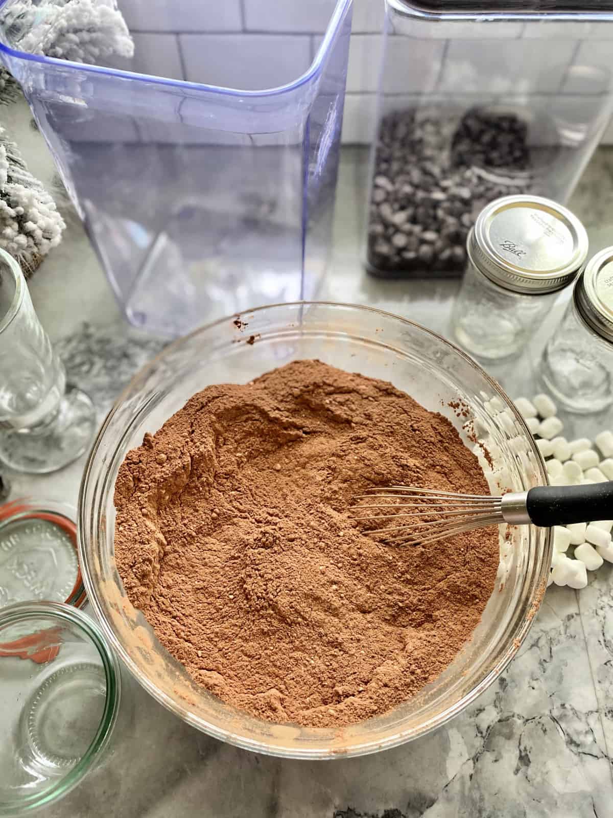Glass bowl filled of cocoa mix with a whisk in the powder mixture.