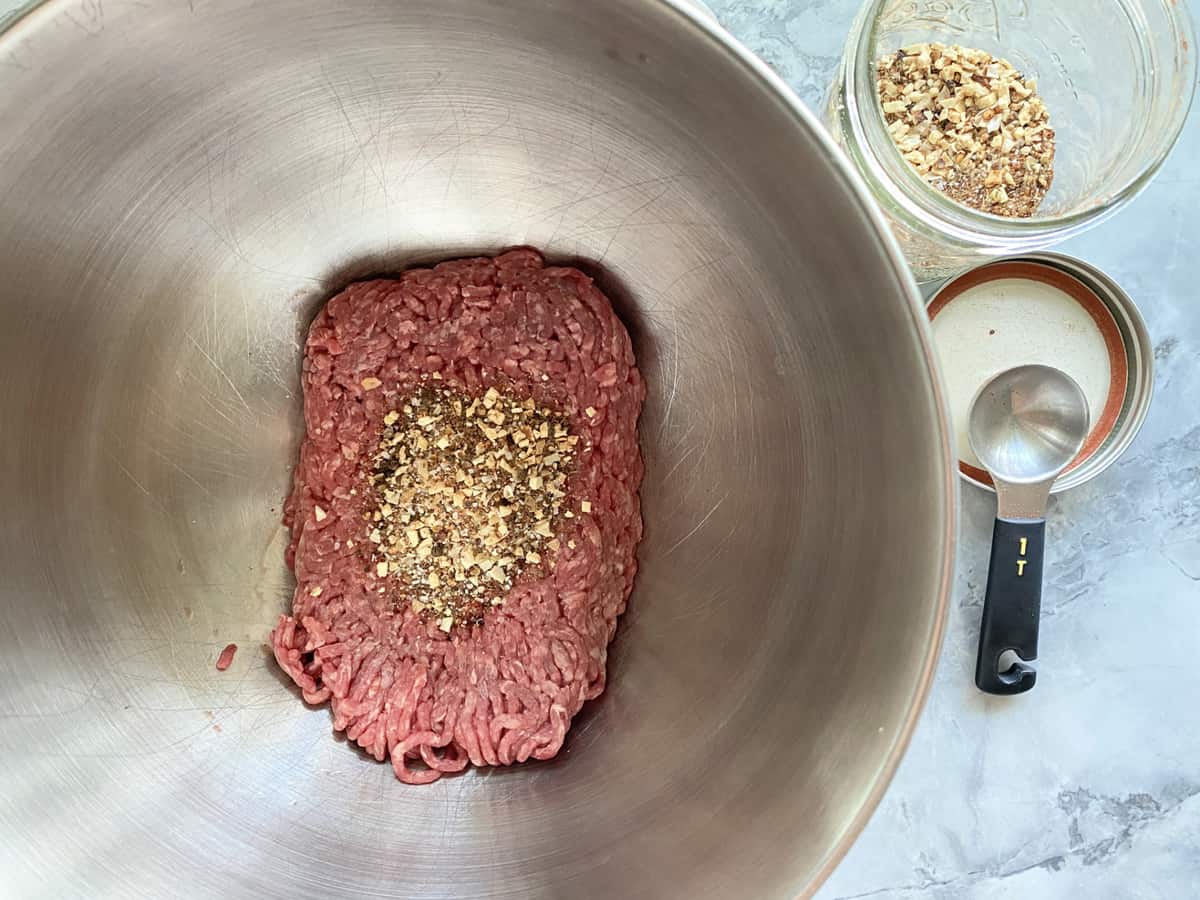 Top view of a bowl of ground beef with spices on top.