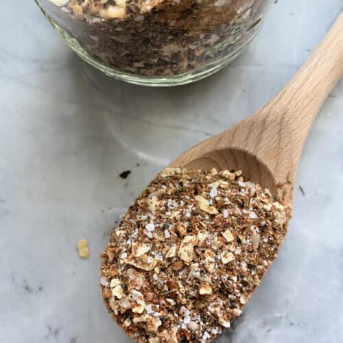 Top view of a wooden spoon filled with spices and a jar next to it.