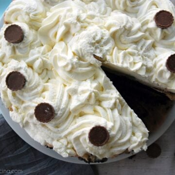 Top view of a piped white cake with a slice cut out of it.