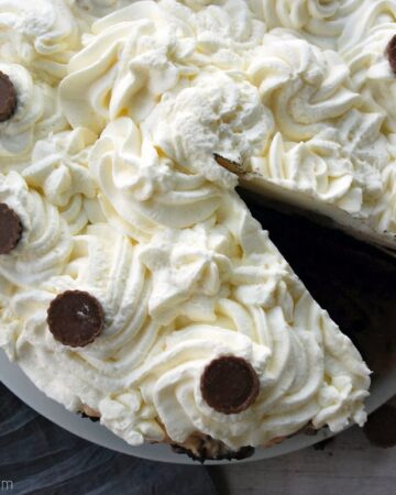 Top view of a piped white cake with a slice cut out of it.