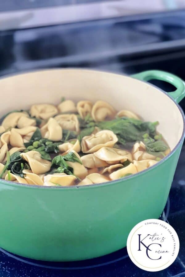 Green cast iron pot simmer on the stove with soup.