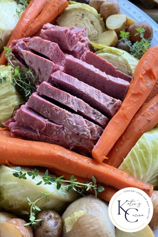 Close up of a platter of corned beef, cabbage, carrots, and potatoes with a logo on the right corner.