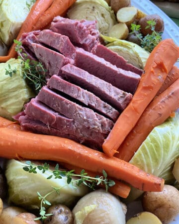 Close up of a platter of beef, carrots, cabbage, and potatoes.