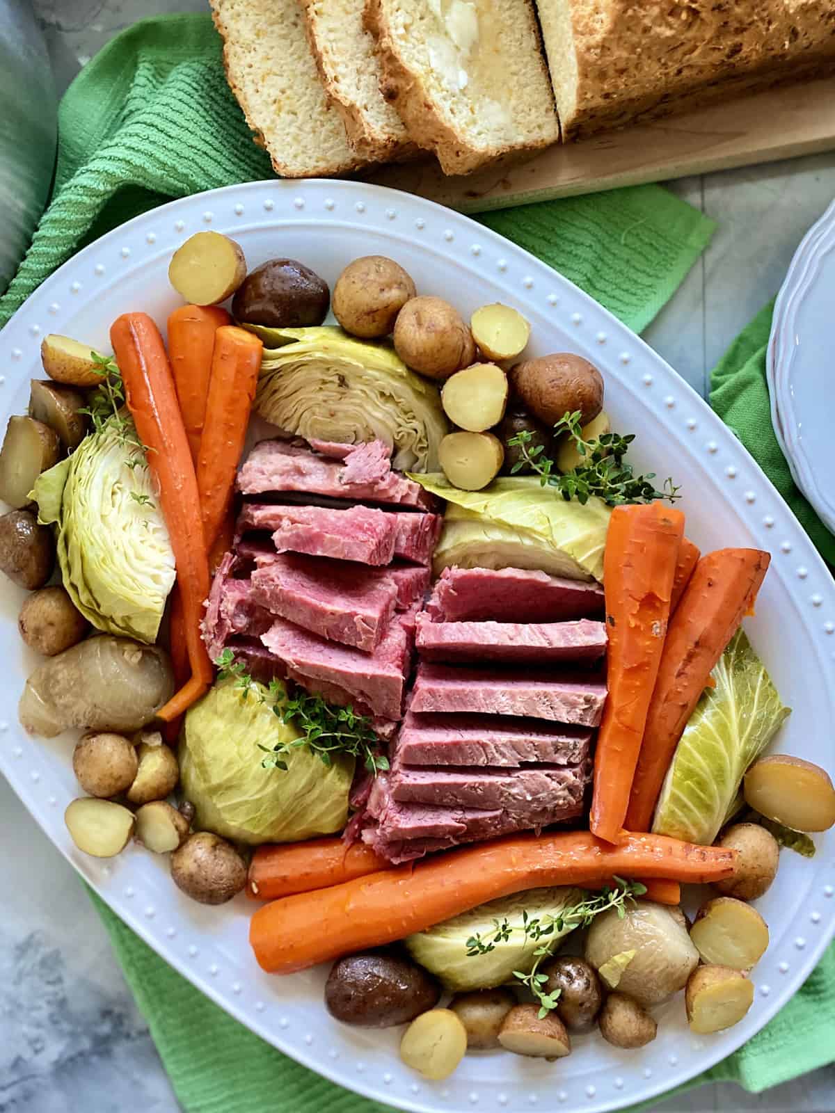 Top view of a white platter filled with beef, carrots, potatoes, and cabbage.