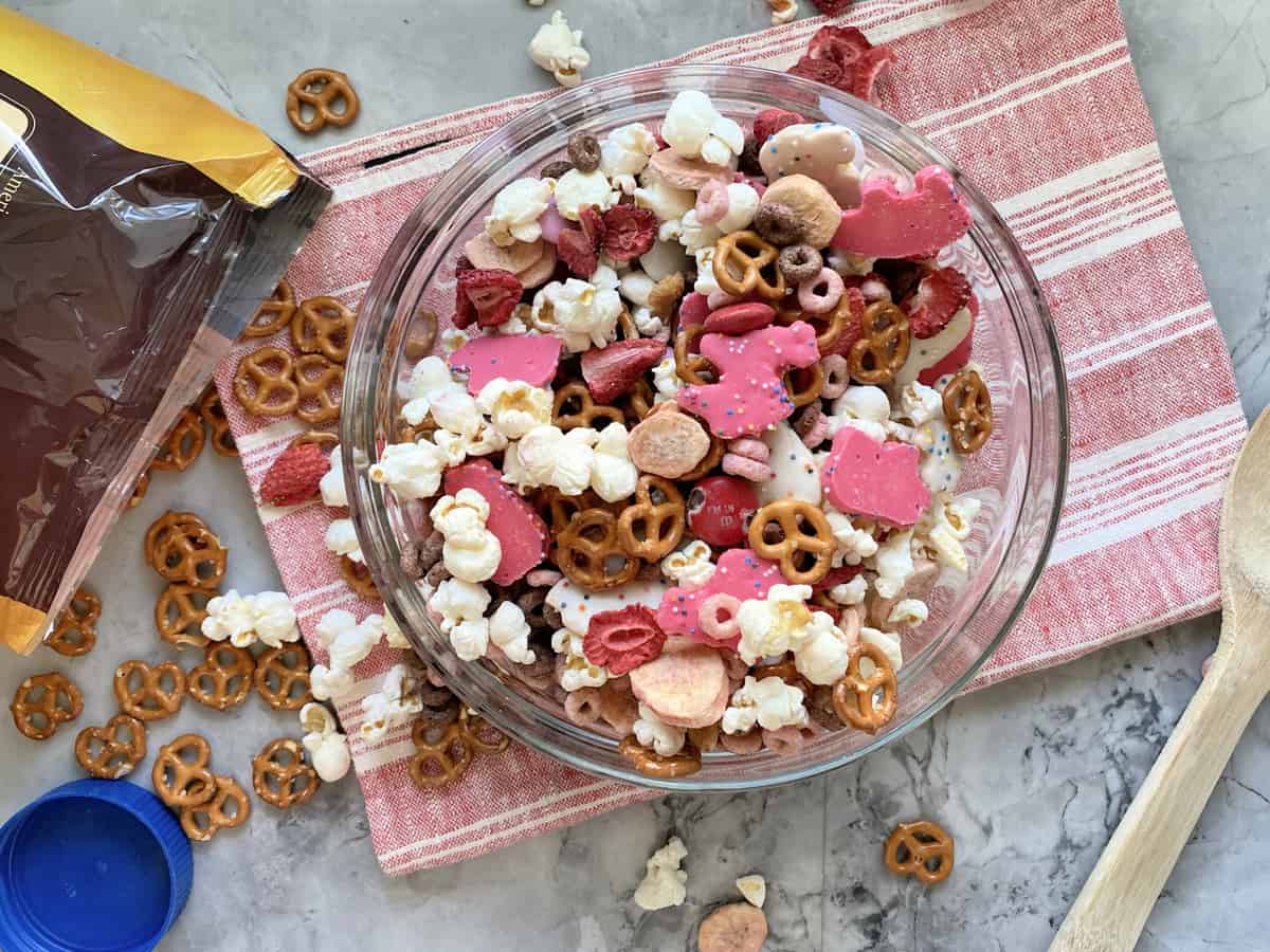 Top view of a bowl of pretzels, popcorn, animal cookies, and strawberries in a bowl.