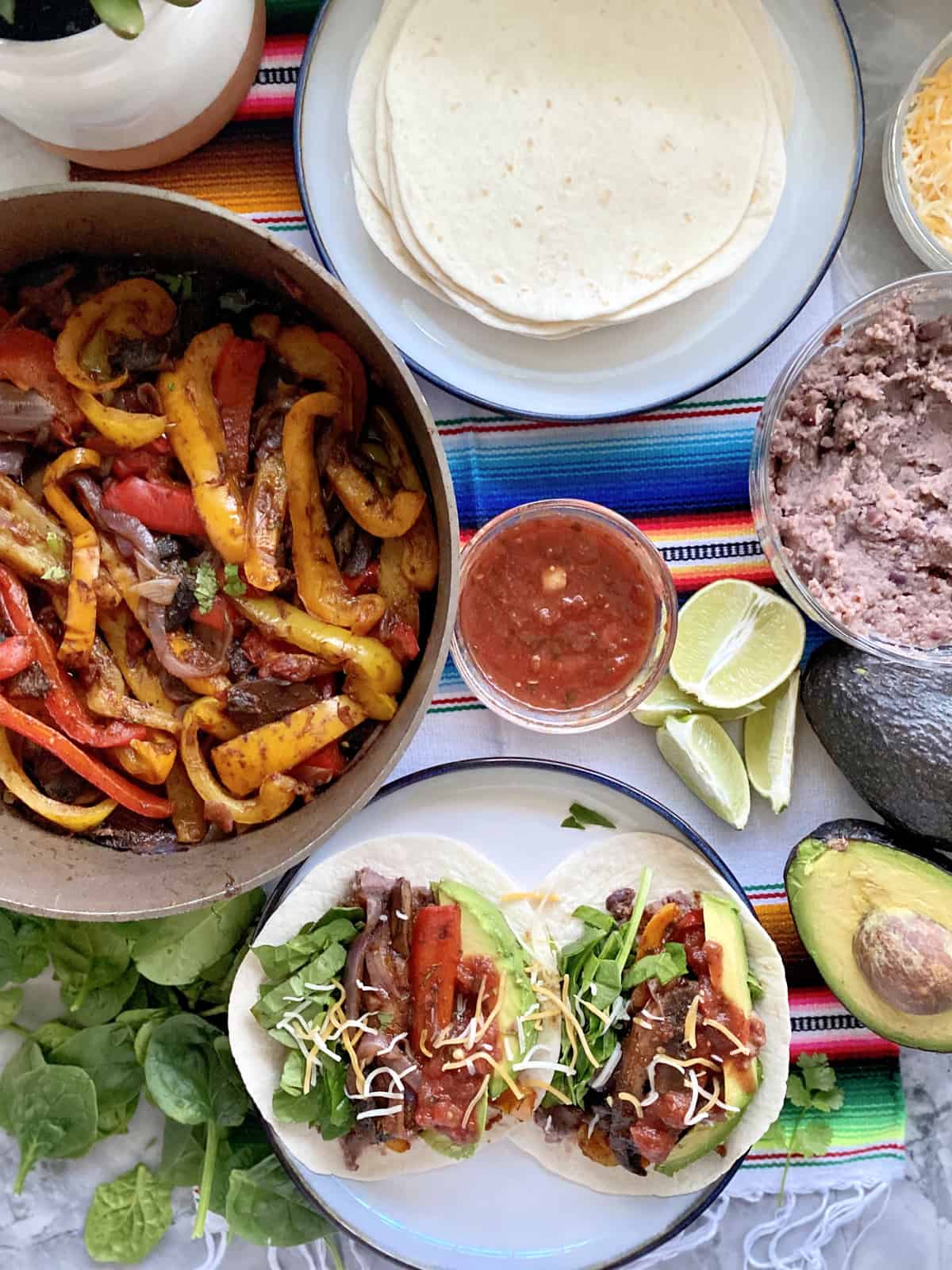 Top view of fajita peppers in a skillet, fajitas on a plate, and tortillas on the side.