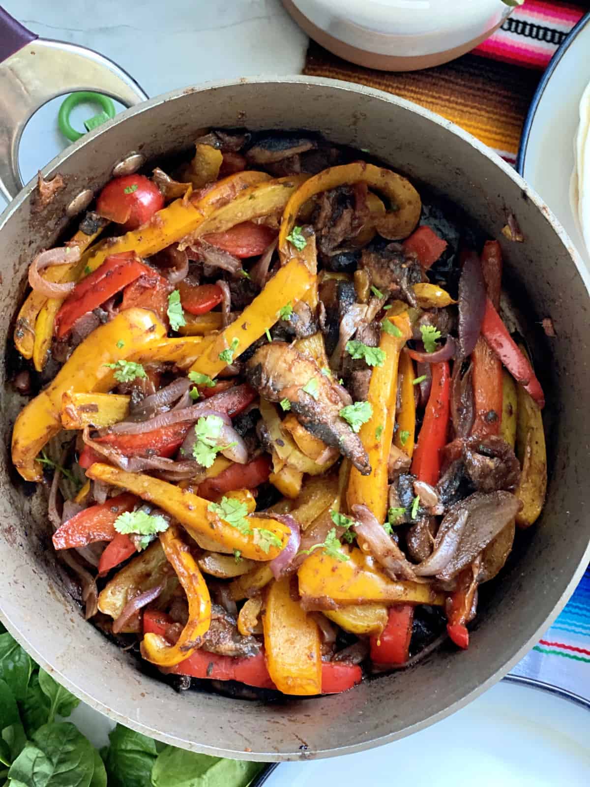 Top view of a skillet with peppers and onions.