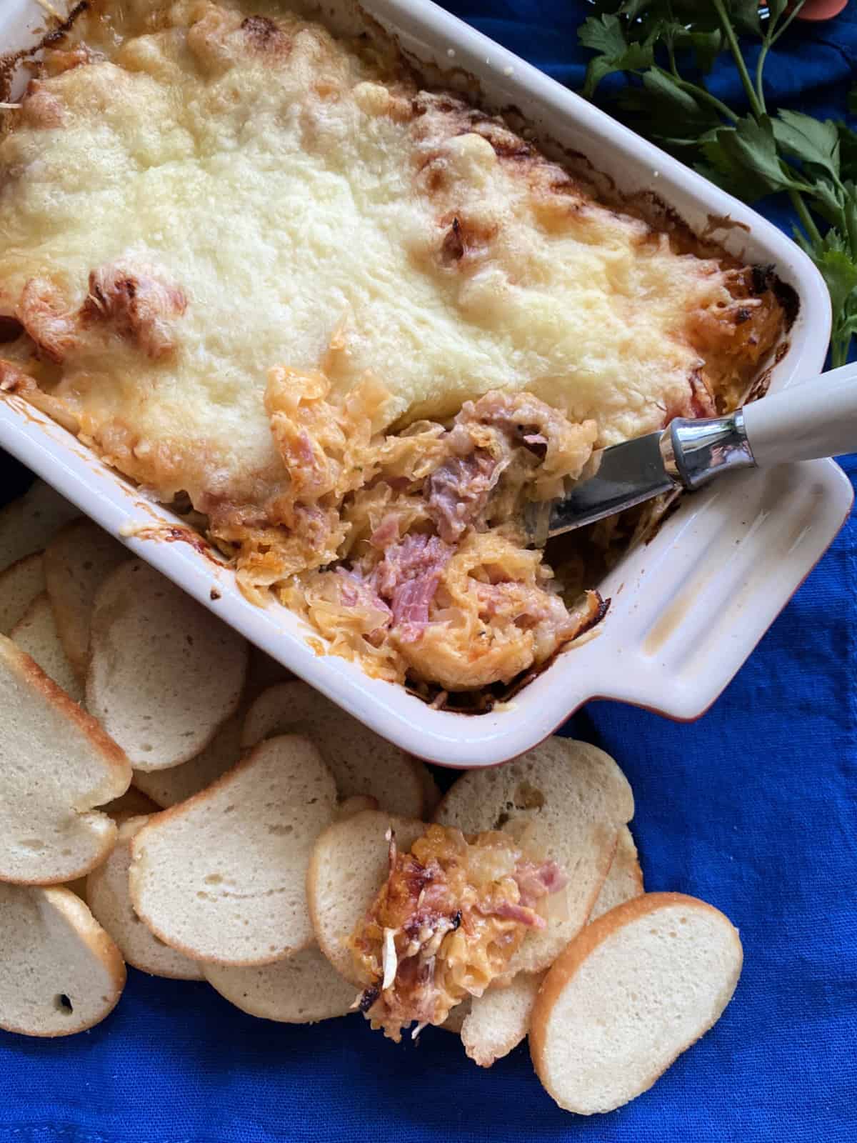 Top view of a baking dish filled with Hot Reuben Dip and baguette next to it.