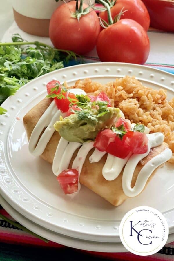 Two white plates with a deep fried Chicken Chimichanga with toppings.