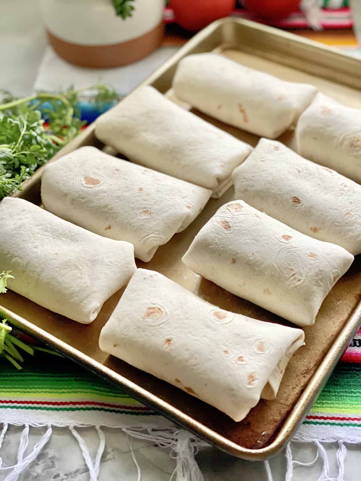 Baking sheet filled with 8 flour burritos.