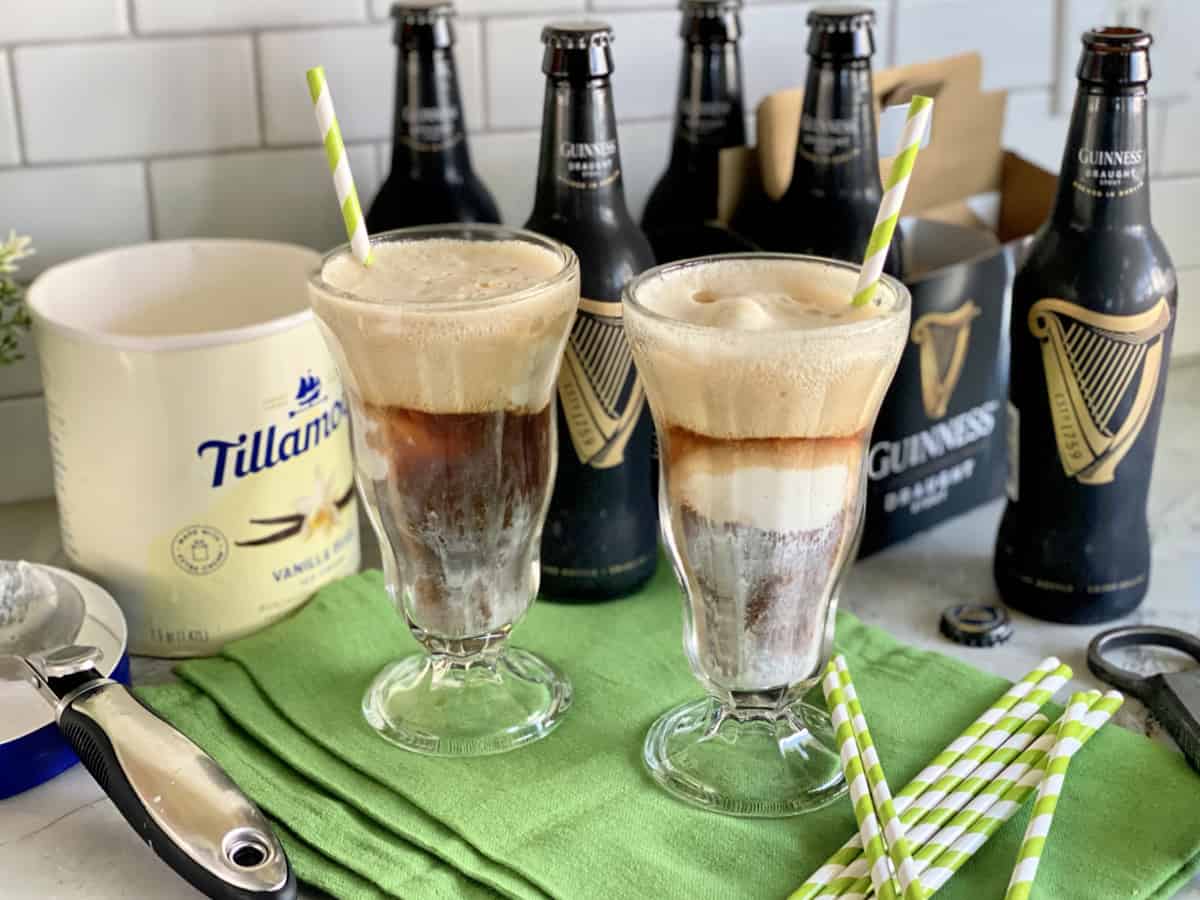 Two glasses filled with ice cream floats with Guinness beer in the background.