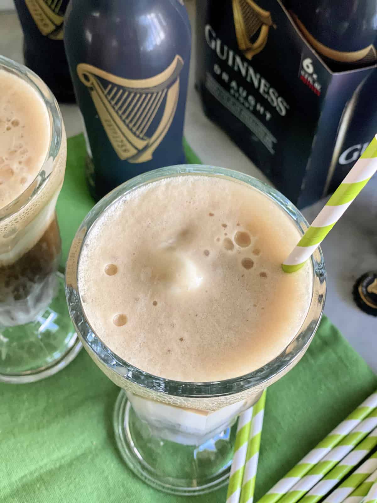 Top view of a beer float with a green and white paper straw.