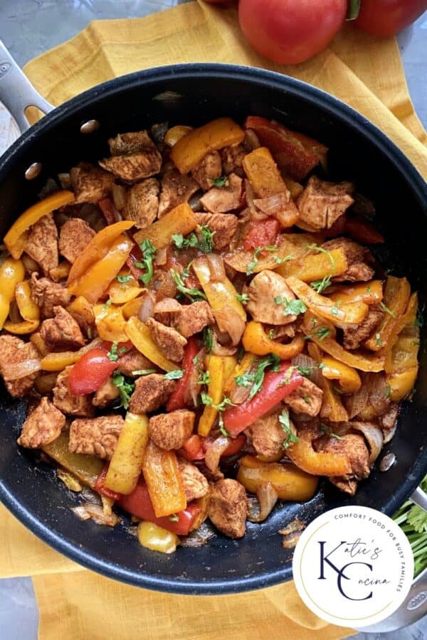 Top view of Skillet Fajitas topped with cilantro and blog logo on right hand corner.