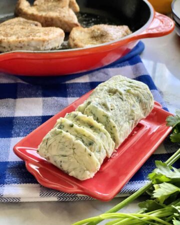 Homemade garlic herb butter on a red serving dish