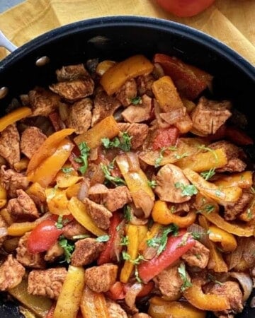 Top view of Skillet Fajitas topped with cilantro and blog logo on right hand corner.