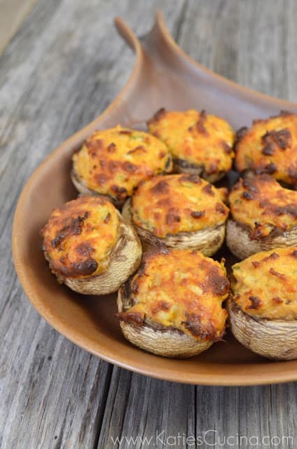 Brown baking dish filled with Buffalo Chicken Stuffed Mushrooms on a wood countertop.