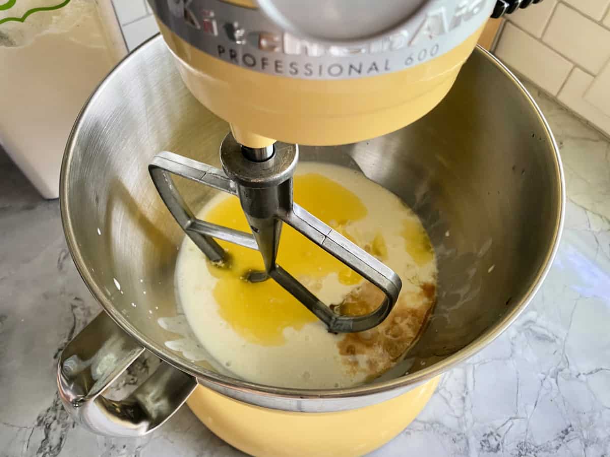 Top view of a yellow KitchenAid mixer with liquids inside the bowl.