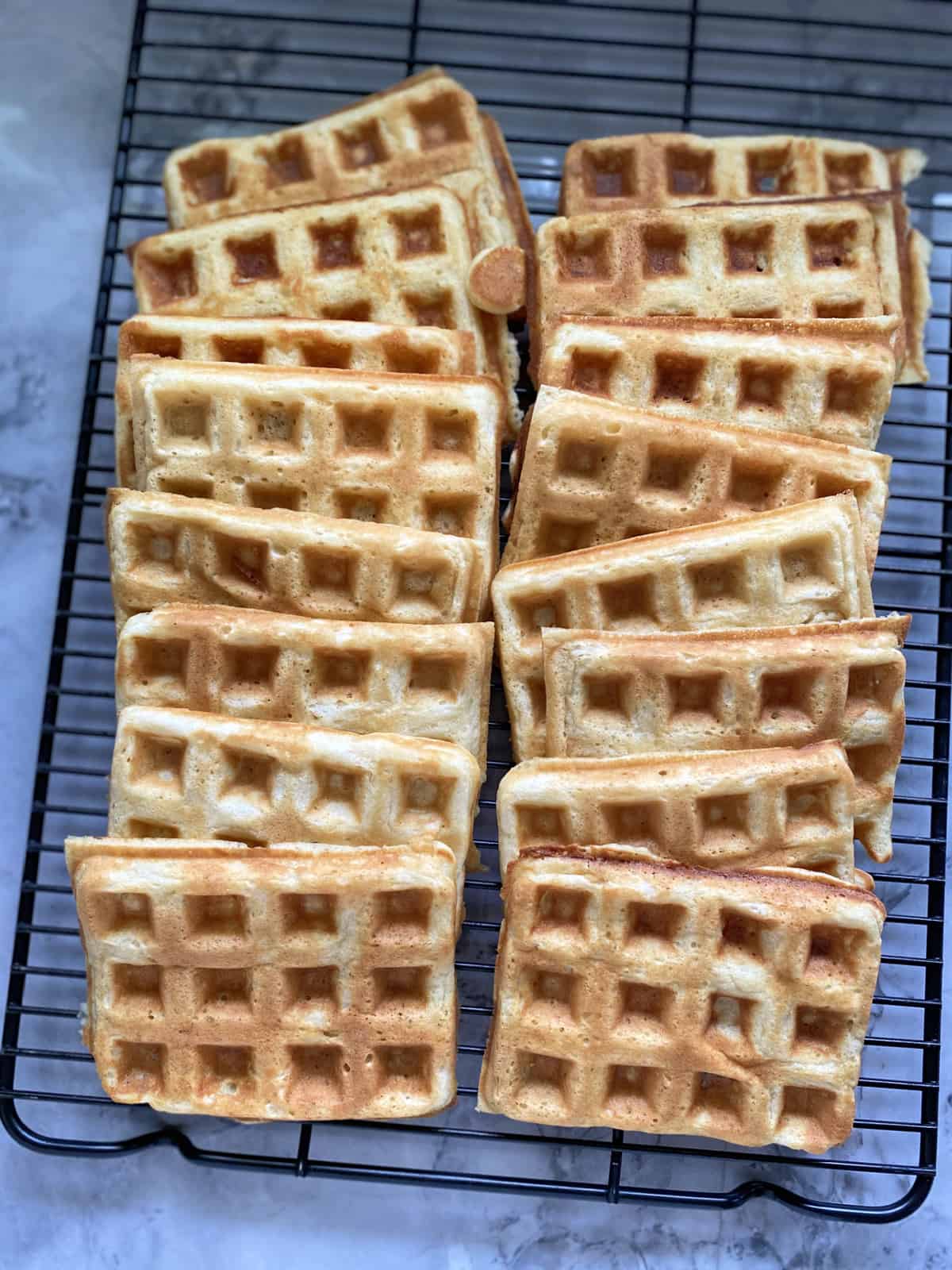 Top view of a black wire rack with rectangular waffles laid out on top of it.